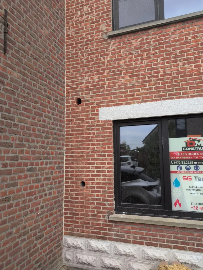 Twee geboorde doorvoeren in de bakstenen gevel voor de ventilatie