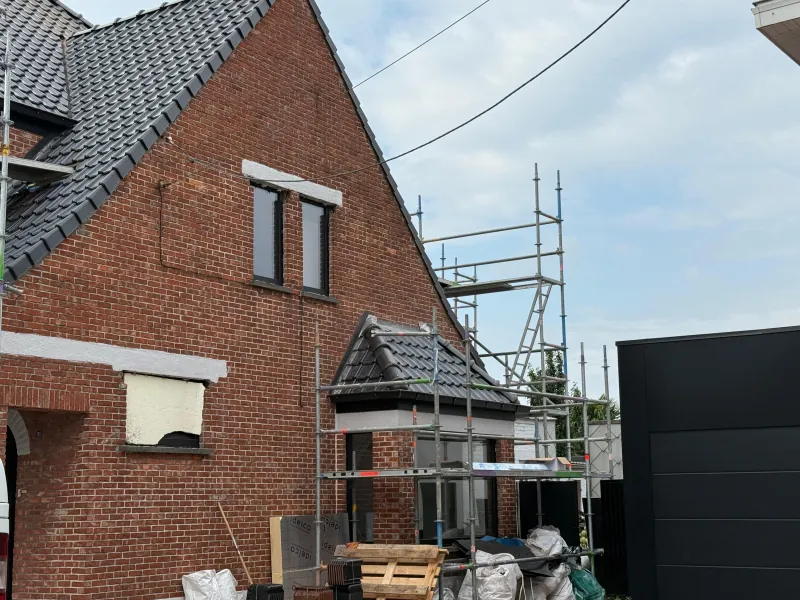 Dakwerken in uitvoering, met stelling rond de woning