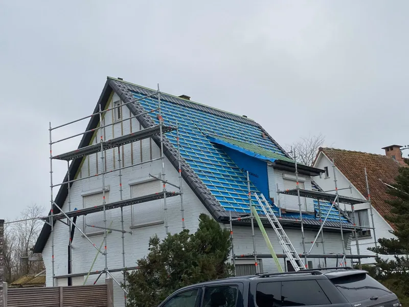 Leikleurige pannen worden gelegd, met het blauwe onderdak nog zichtbaar