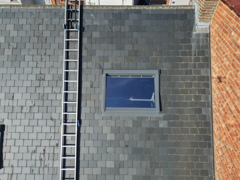 Nieuw dakraam in een leien dak, gezien van bovenaf, met een ladder ernaast